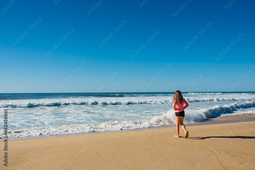 pretty little girl barefoot by the turquoise ocean