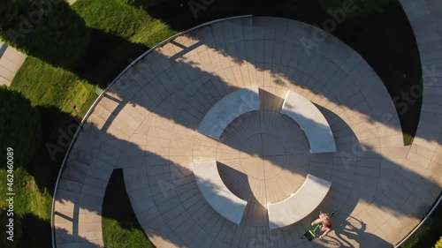 a woman on a bicycle rides in a circle view from above, shooting from a drone that rotates behind the object