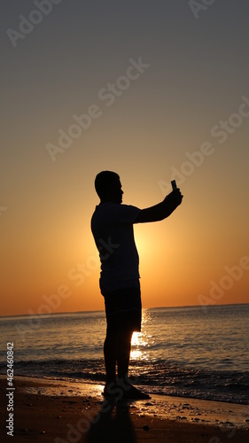 Young man taking a selfie at sunset at the seaside