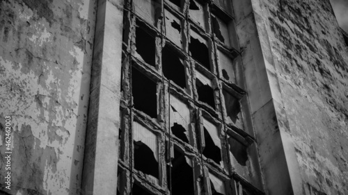 Grayscale shot of old broken windows of an abandoned building - horr photo