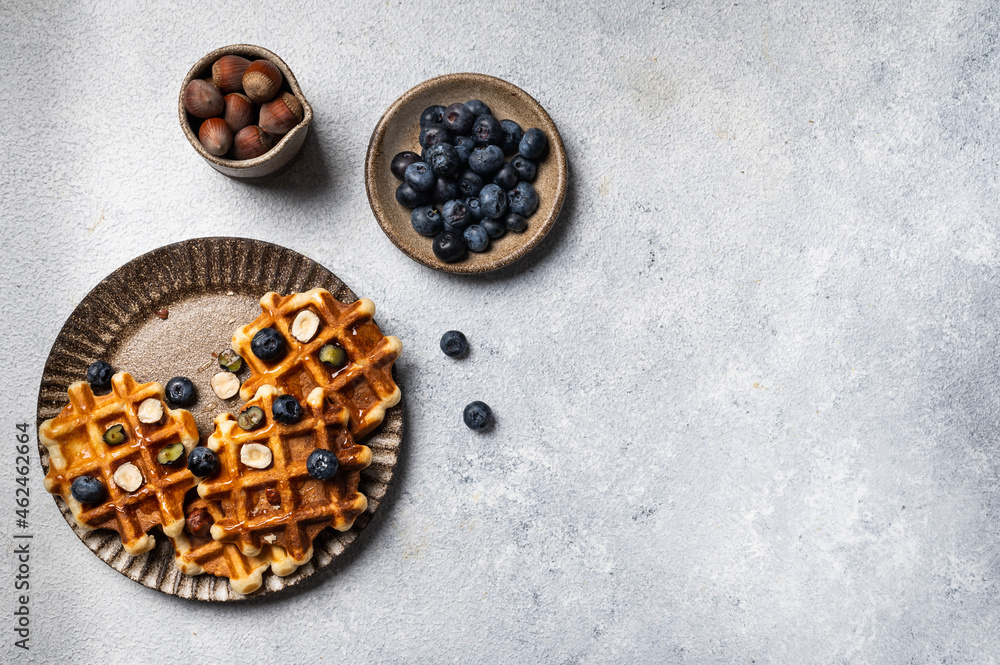 Freshly made belgian waffles with blueberry and hazelnut. Waffles with honey and berry. Place for text. Copy space. Classic sweet breakfast Freshly made belgian waffles with blueberry and hazelnut. Waffles with honey and berry. Place for text. Copy space. Classic sweet breakfast