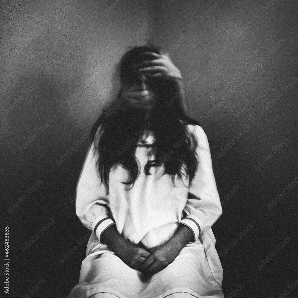 Creepy ghost girl sitting in chair with eerie hands grabbing her face