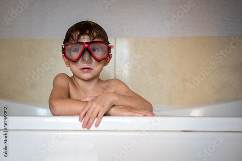 Portrait young boy leaning on bathtub edge wearing a diving mask
