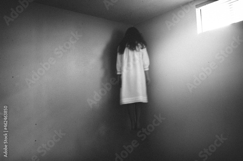 Scary girl in nightgown hovering in the corner of room photo