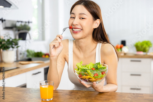 Close up Happy Asian healthy woman smiled and holding vegetable salad and eat small tomato to diet and eat clean food