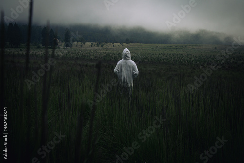 One man wearing a white hoodie staring at a foggy grassland photo