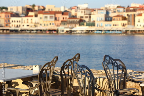 view of the harbor of the city of island, Chania, Crete, decorative chairs in cafe, in background sea bay and architecture of town