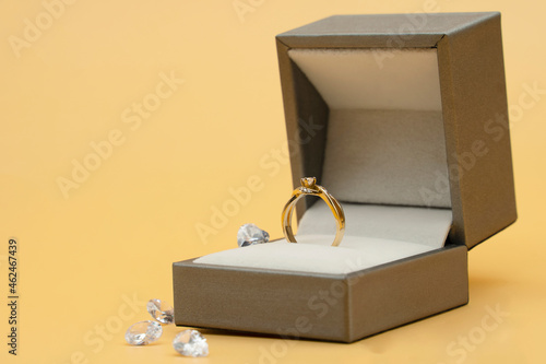 Diamond ring in jewelry gift box on yellow background