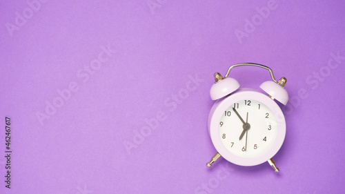 Purple alarm clock on purple background