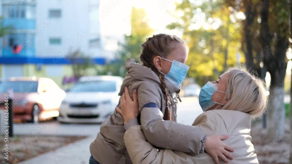 A child in a medical mask runs to his mother and hugs her. A child in a medical mask runs to his mother and hugs her. Mom meets her daughter after school and removes the medical mask from her face. A child in a medical mask runs to his mother and hugs her. A child in a medical mask runs to his mother and hugs her. Mom meets her daughter after school and removes the medical mask from her face.