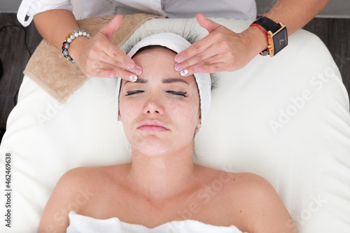 Facial treatment that allows women to rejuvenate. Dermatologist applies a facial treatment to a young white woman, who is lying in a clinic specializing in skin rejuvenation.