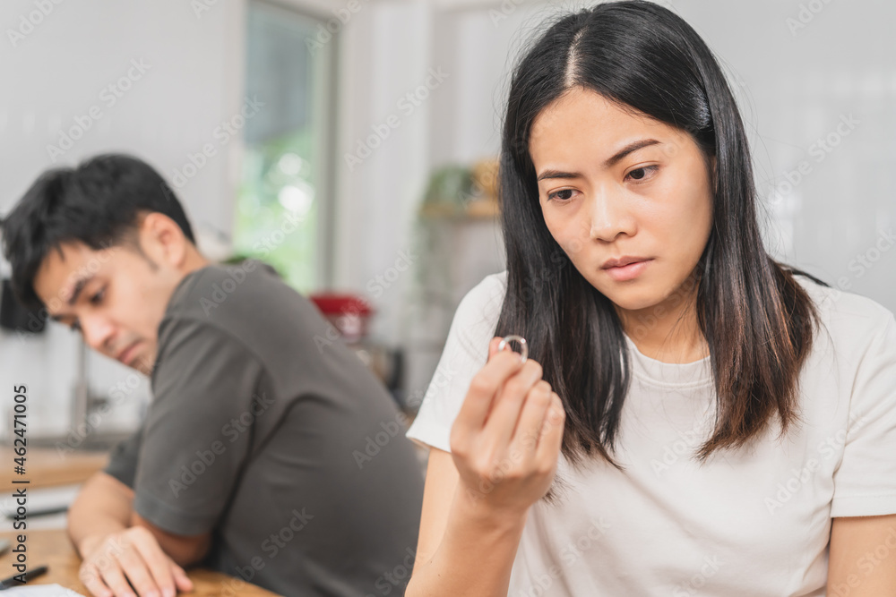 Stress, unhappy asian young couple man, woman quarrel on couch, relationship in trouble. Wife holding wedding ring in disappointment and upset her husband, which may lead to divorce. Problem of family Stress, unhappy asian young couple man, woman quarrel on couch, relationship in trouble. Wife holding wedding ring in disappointment and upset her husband, which may lead to divorce. Problem of family