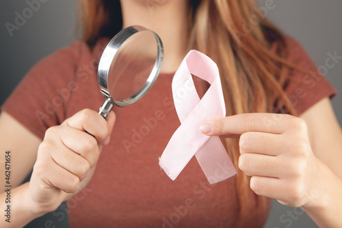 woman magnifying glass looking at pink ribbon