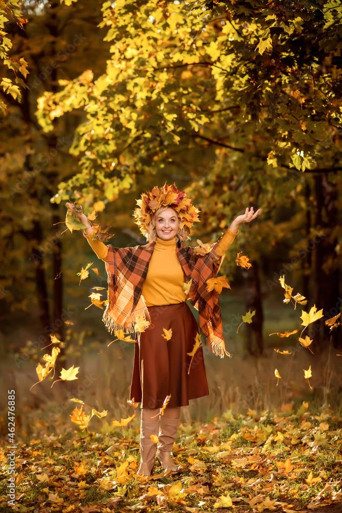 An elderly woman walks in the autumn forest. Throws yellow leaves up An elderly woman walks in the autumn forest. Throws yellow leaves up
