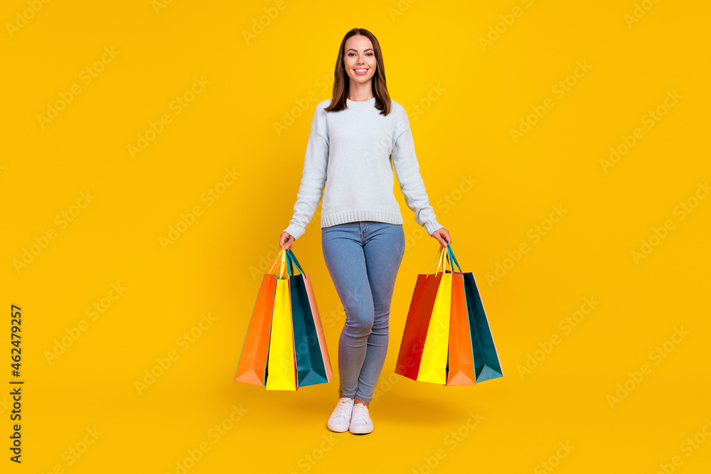 Full body photo of happy cool woman hold hands shopping bags smile isolated on yellow color background