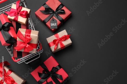Cart with gift boxes on dark background, flat lay and space for text. Black Friday sale