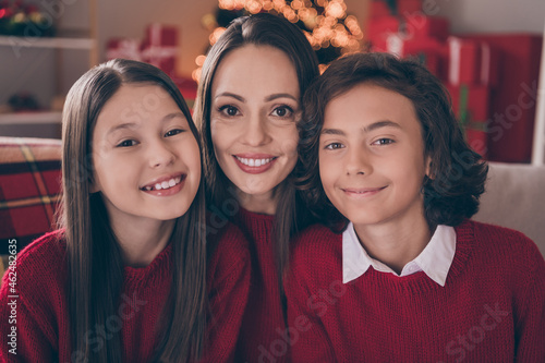 Photo of attractive cute mom son daughter wear red pullovers smiling celebrating christmas hugging indoors house home room