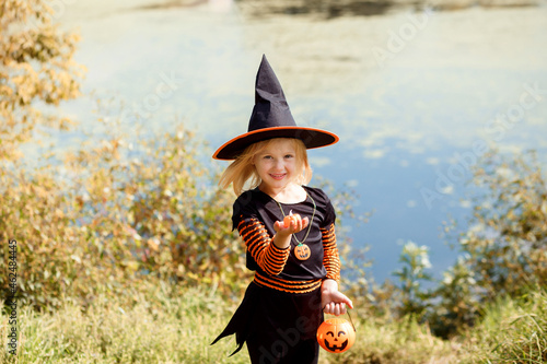 Funny blonde girl in Halloween costume holds jack o lantern, trick or treat.