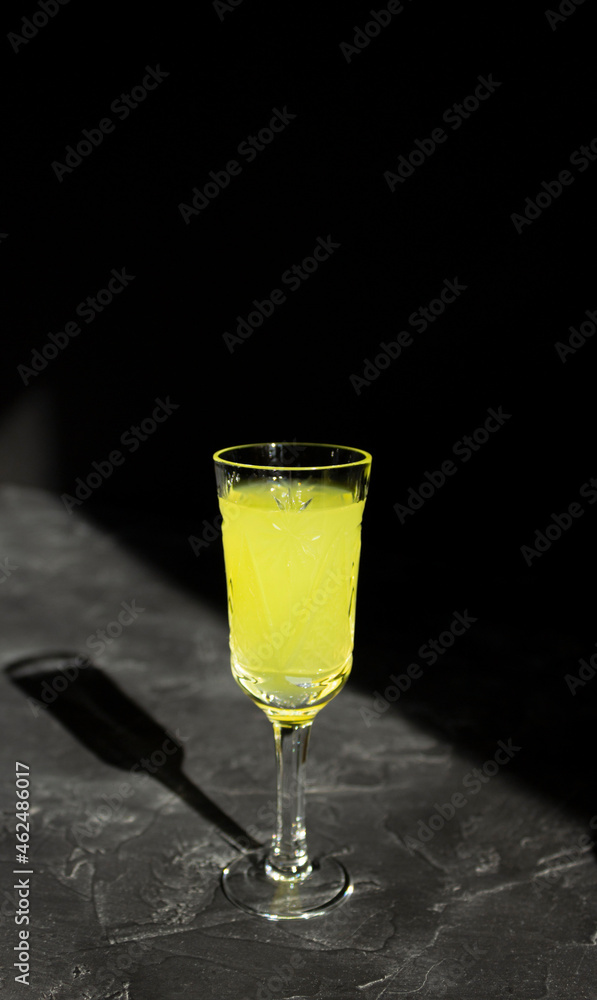 Limoncello liqueur or poncha drink with copy space on black surface in bright sunlight