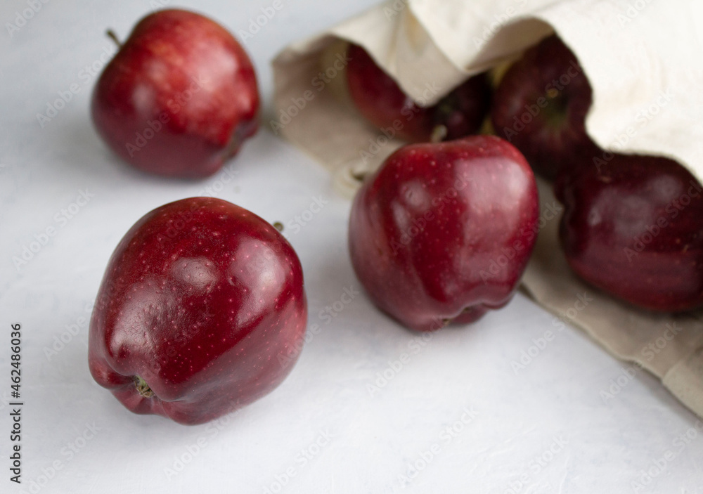 Obraz premium Red chief apples rolled out of a linen eco bag on a white surface