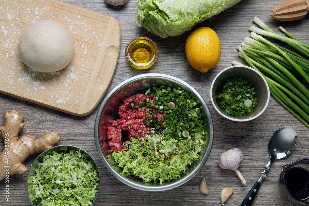Bowl with gyoza filling, raw dough and ingredients on wooden table, flat lay Bowl with gyoza filling, raw dough and ingredients on wooden table, flat lay