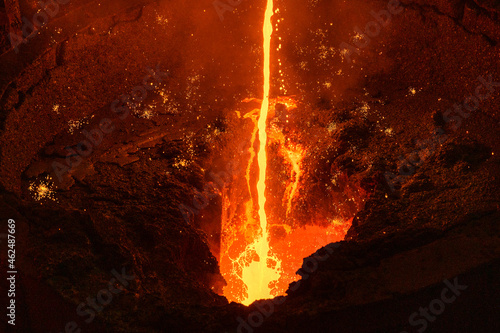 Molten iron. Liquid metal is poured into the ladle in a thin stream.