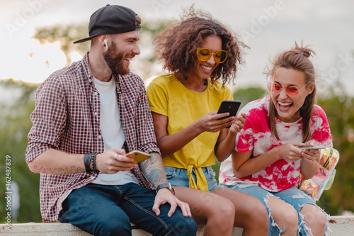 happy young company of smiling friends sitting in park