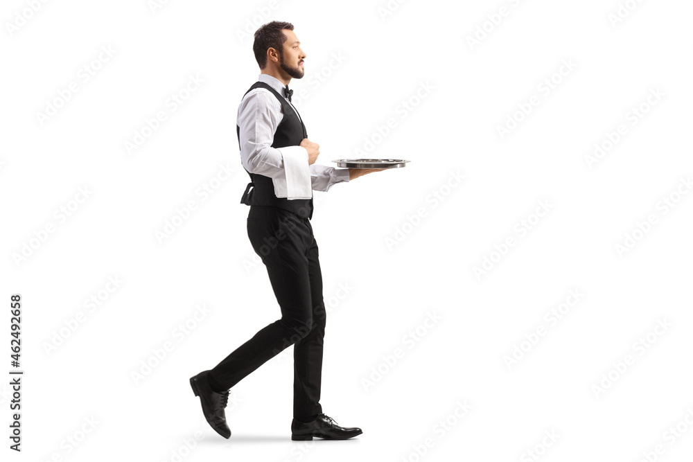 Full length profile shot of a waiter carrying a silver tray and walking Full length profile shot of a waiter carrying a silver tray and walking