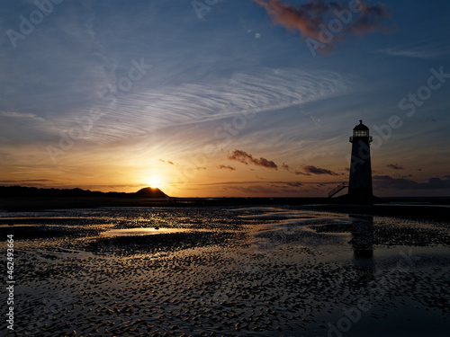 The sun setting behind the dunes against the Point of Ayr Lighthouse on Talacre, North Wales.