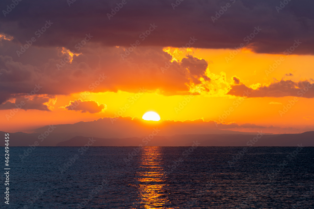 Stunning dramatic, cloudy sunrise with a bright sun rising over a calm water. Natural background, Sardinia, Italy.
