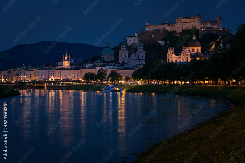Panoramic view of illuminated Salzburg skyline with river Salzach in summertime at night, Austria