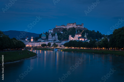 Panoramic view of illuminated Salzburg skyline with river Salzach in summertime at night, Austria