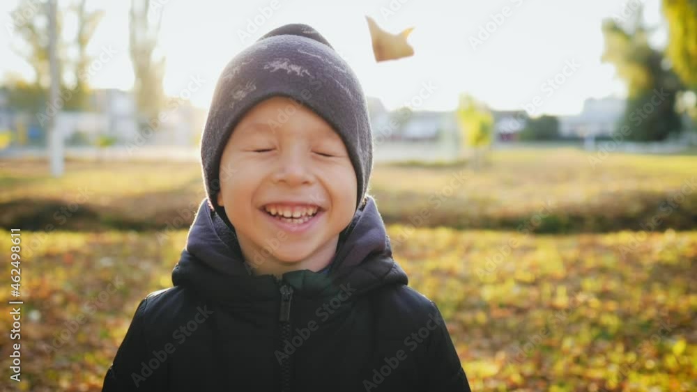Autumn walk. A boy throws a pile of leaves overhead and watches them fall. Kid playing with the golden leaves in autumn park. Happy family on autumn walk. People in park. Happy family concept. Autumn walk. A boy throws a pile of leaves overhead and watches them fall. Kid playing with the golden leaves in autumn park. Happy family on autumn walk. People in park. Happy family concept.