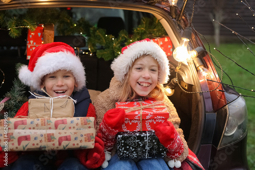 New Year's mood, brother and sister are sitting in a car full of gifts, children are having fun, rejoicing and choosing gifts