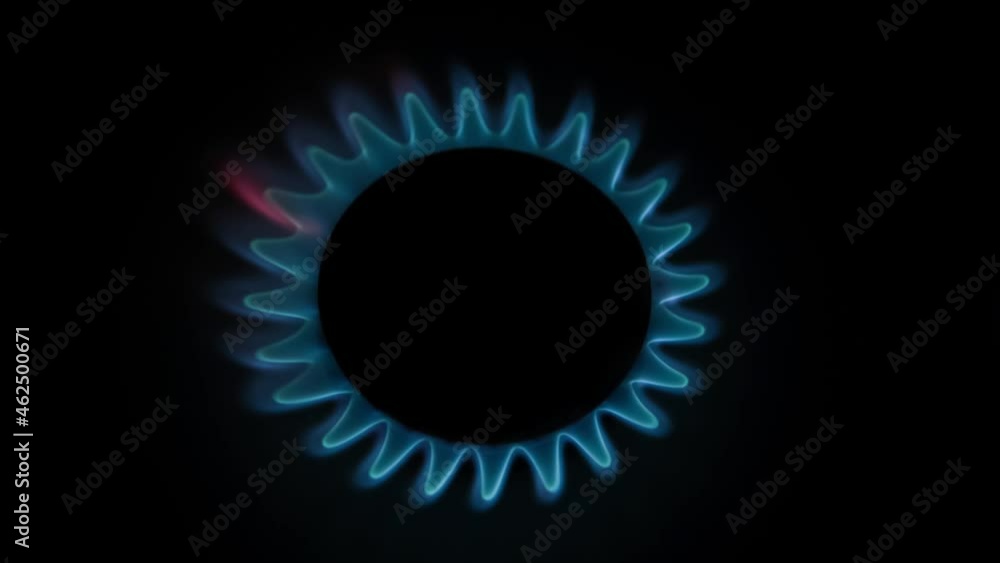 Top view of burning gas stove with blue flame in dark kitchen. Black background. Copy space for your text. Selective focus. Biogas or natural gas. Fuel industry theme.
