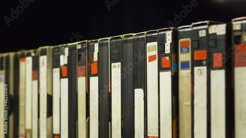 a man's hand pulls out a videotape from the shelf