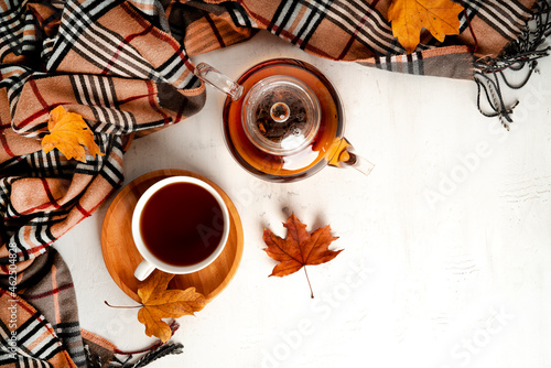 Autumn composition. A cup of tea and teapot  scarf  autumn leaves. Flat lay  top view  copy space
