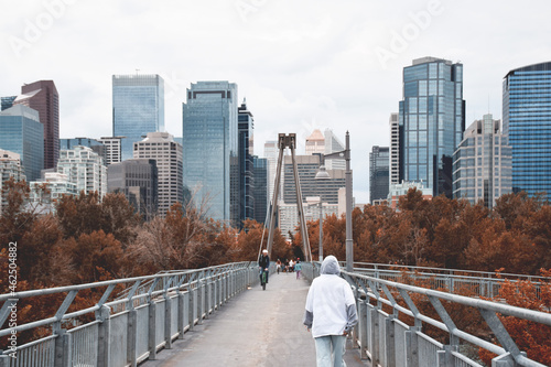 Young teenage girl from behind walking on bridge with city in front of her