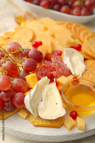 Platter with crunchy crackers, cheese and honey, closeup