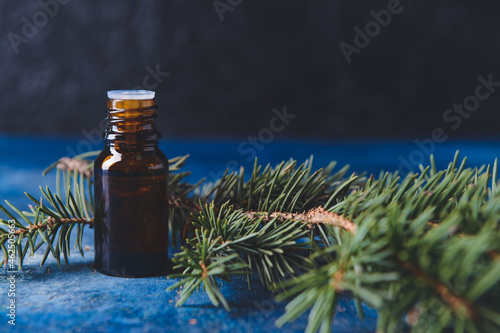 Bottle of coniferous essential oil on dark background