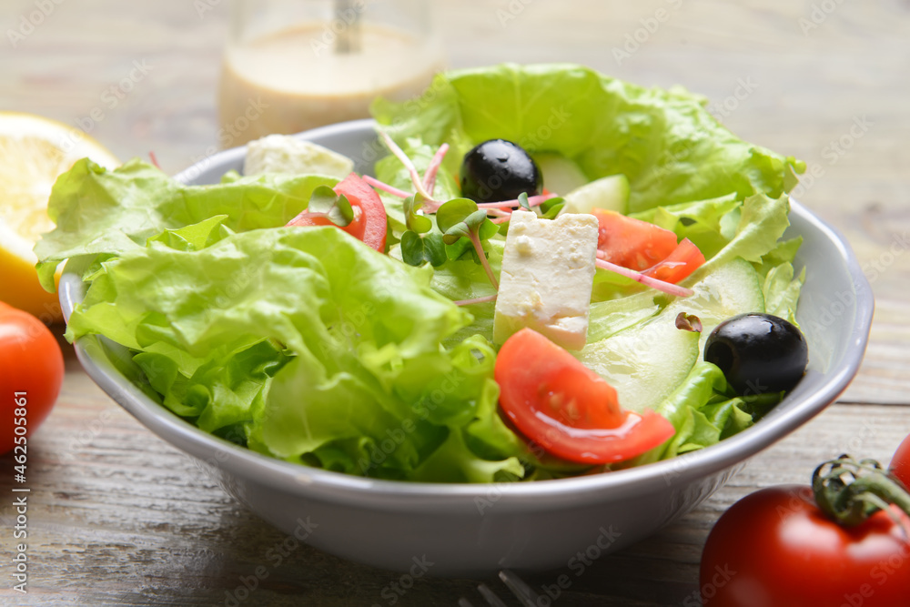 Plate with healthy salad with feta cheese and olives on wooden background Plate with healthy salad with feta cheese and olives on wooden background