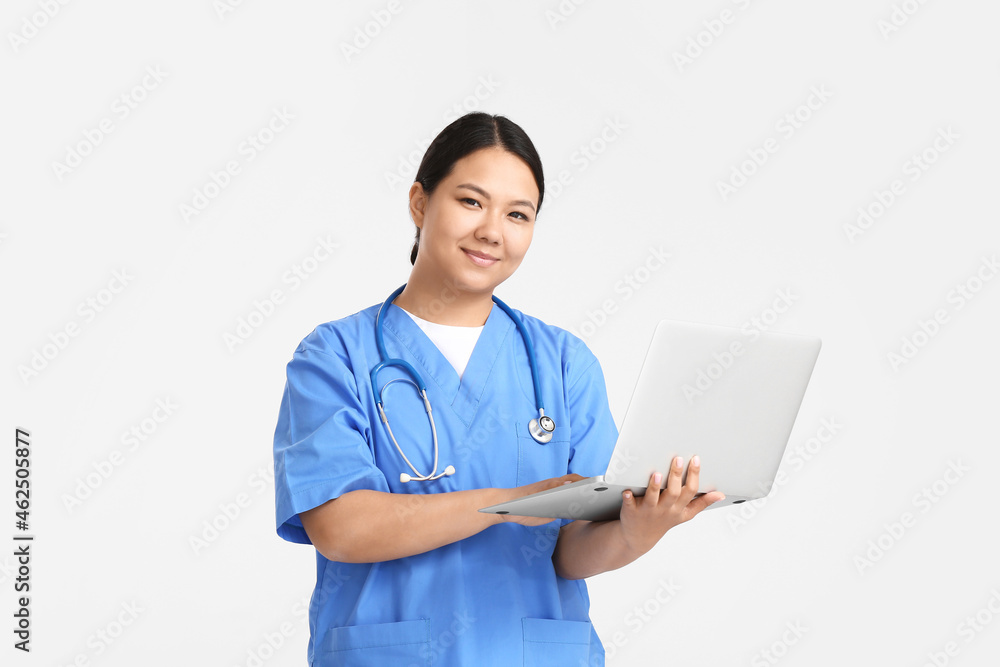 Portrait of female Asian doctor with laptop on light background Portrait of female Asian doctor with laptop on light background