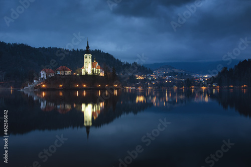 A mysterious evening view of Lake Bled, Slovenia. Landscape with the lights of the city at night. Church on an island, postcard view, national park.