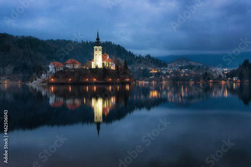 A mysterious evening view of Lake Bled  Slovenia. Landscape with the lights of the city at night. Church on an island  postcard view  national park  Julian Alps.