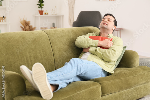 Young man with book listening to music at home