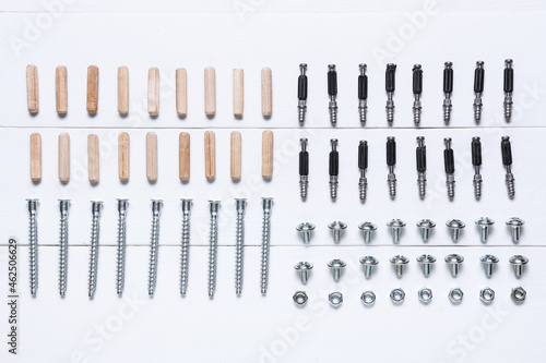 Set of bolts  nuts and dowels on white wooden background