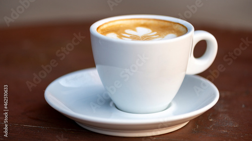 White cup of espresso coffee on wooden table. Space to copy your text.