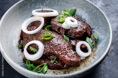 Modern style traditional Cuban dry aged angus bistec encebollado steak with onion rings in soy sauce served as close-up in a Nordic design bowl photo