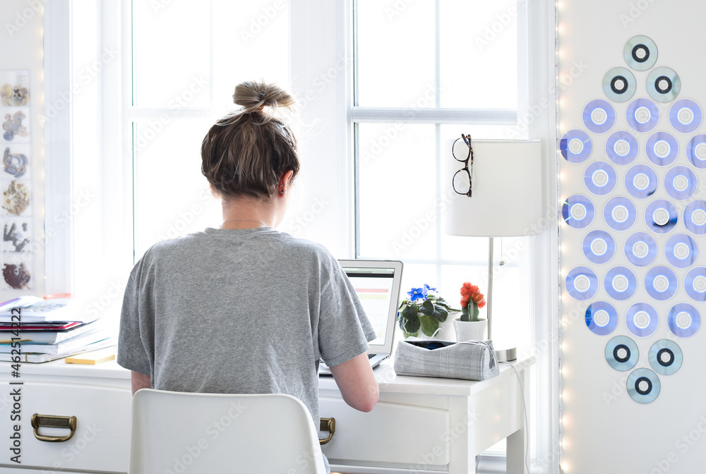 Young teen girl student sitting at desk in her room studying using laptop computer Young teen girl student sitting at desk in her room studying using laptop computer