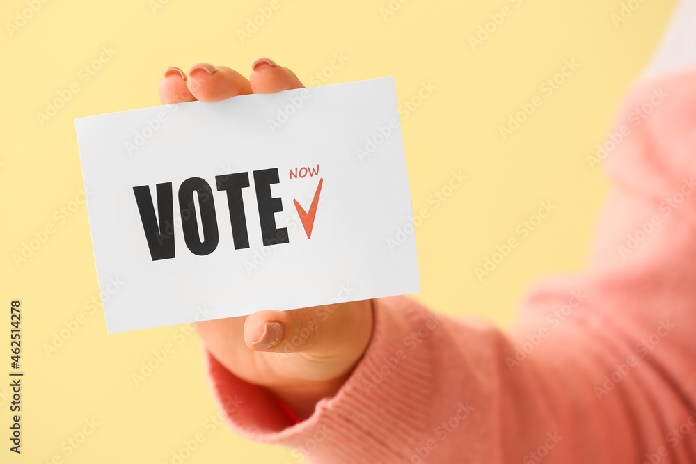 Woman holding paper with text VOTE on color background Woman holding paper with text VOTE on color background